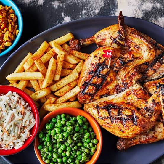 A flame-grilled peri-peri chicken platter with fries and sides at Nando’s.
